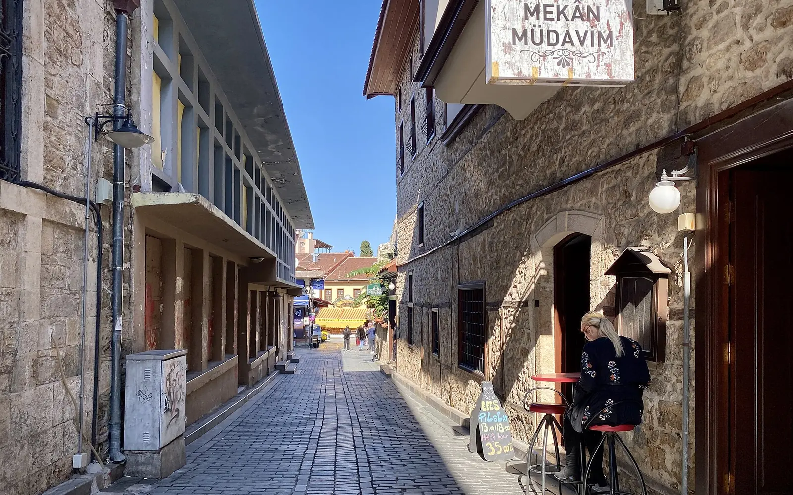 A café-lined street in Kaleiçi with the Yivli minaret behind